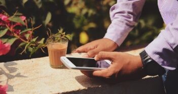 man using smartphone beside drinking glass