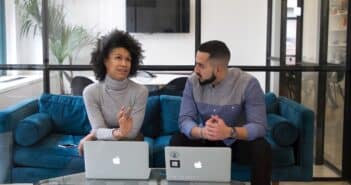 a man and a woman sitting on a couch with their laptops