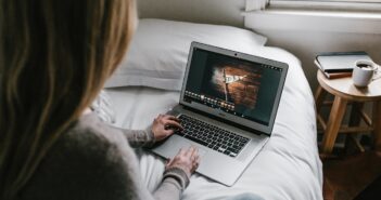 woman using gray laptop on bed