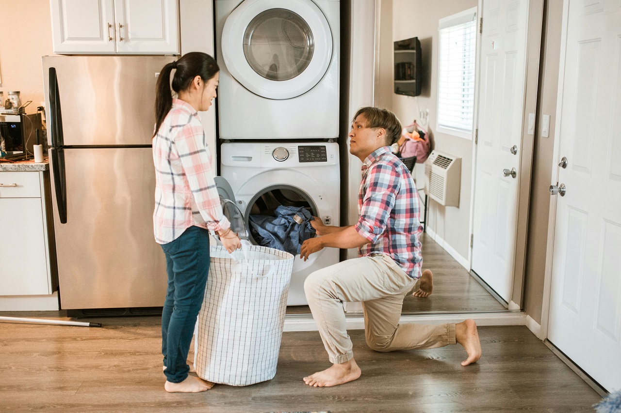 Un couple asiatique remplissant de linge le tambour d'un lave-linge.