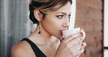 woman leaning on wall drinking coffee