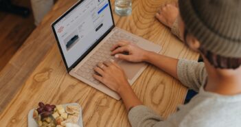 Person sitting on a table clicking on their Surface laptop