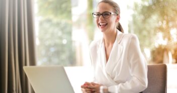 Laughing businesswoman working in office with laptop