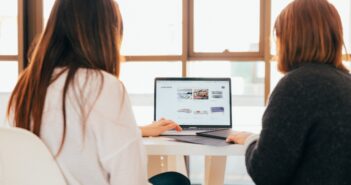 two women talking while looking at laptop computer