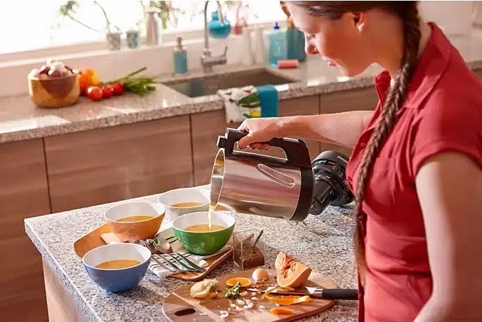 Une femme dans une cuisine remplissant des bols de soupe avec un blender SoupMaker