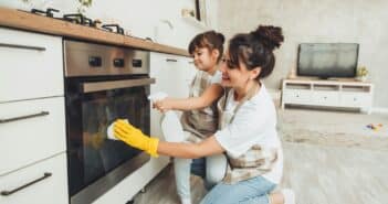 A little girl and her mother are cleaning the kitchen.woman and child wipe the oven in the kitchen