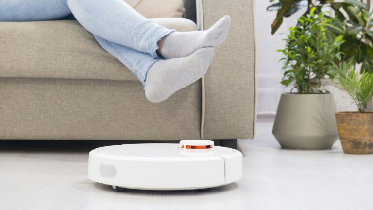 girl resting at home on the couch, while the robot vacuum cleaner. Time for yourself. smart House.