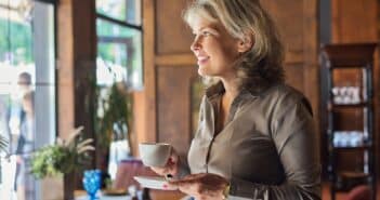 Mature beautiful woman in restaurant with cup of coffee