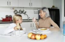 mother and daughter eating fruit in the kitchen. family time