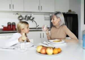 mother and daughter eating fruit in the kitchen. family time