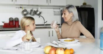 mother and daughter eating fruit in the kitchen. family time