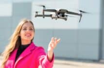 Start the drone, launching from hands. Defocused young woman in the background, focus on the drone