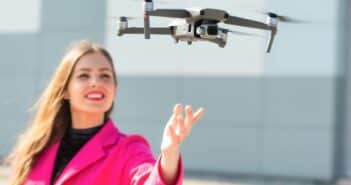 Start the drone, launching from hands. Defocused young woman in the background, focus on the drone