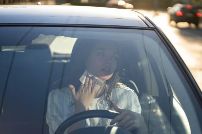 Woman driver being hot during heat wave in car, suffering from hot weather wipes sweat from neck