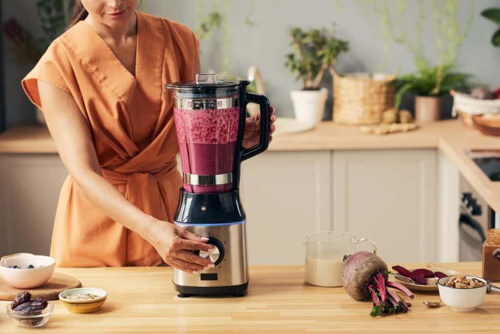 Young housewife with electric blender preparing smoothie