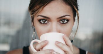 woman drinking from white coffee cup