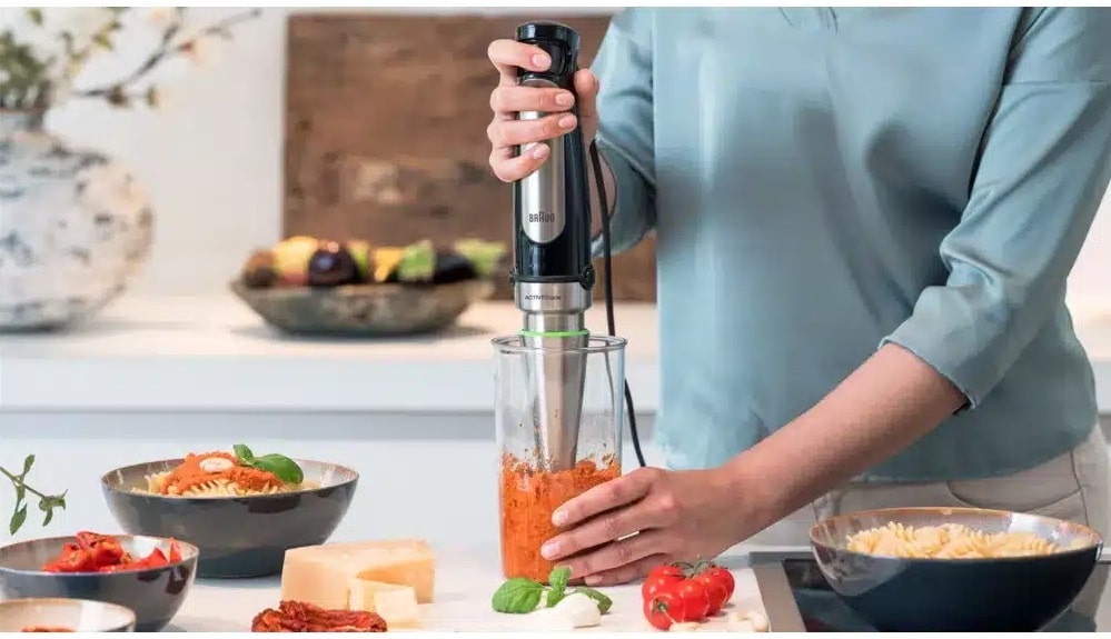 Femme mixant des légumes avec un blender plongeant de Braun