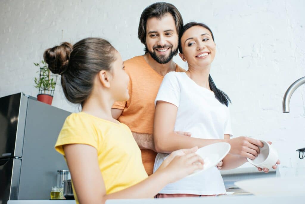 beautiful young family washing dishes together at kitchen