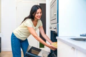 Casual woman cooking pizza in the oven