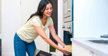 Casual woman cooking pizza in the oven