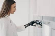 Happy disabled woman with robotic cyber hand switching oven on. Cooking at home using bionic limb.