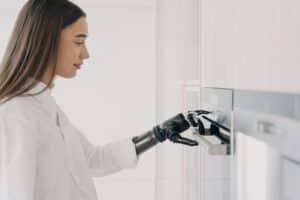 Happy disabled woman with robotic cyber hand switching oven on. Cooking at home using bionic limb.