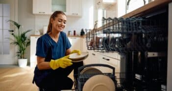 Happy woman putting dishes in the dishwasher.