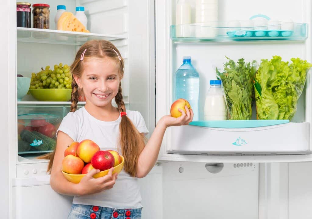 little girl holding apples from fridge