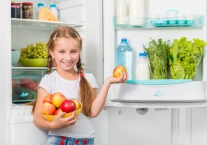 little girl holding apples from fridge