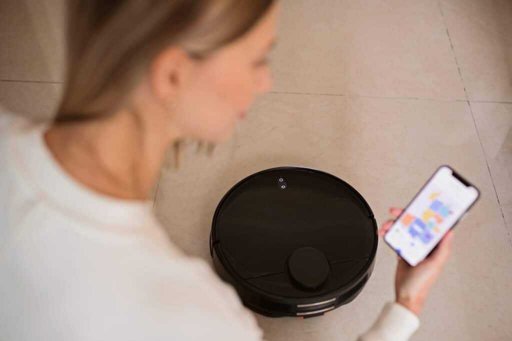 Robotic vacuum cleaner cleaning the room while woman relaxing. Woman controlling vacuum with remote