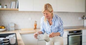 Senior woman loading or unloading dishwasher indoors at home