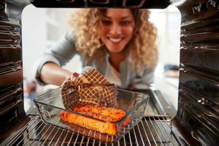 View Looking Out From Inside Oven As Woman Cooks Oven Baked Salmon