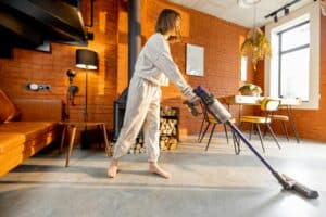 Woman cleaning floor with handheld vacuum cleaner