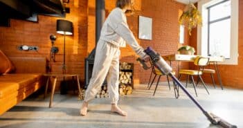 Woman cleaning floor with handheld vacuum cleaner