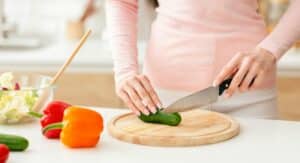 Woman Cutting Up a Cucumber on a Cutting Board, Cropped