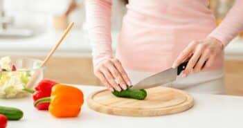 Woman Cutting Up a Cucumber on a Cutting Board, Cropped