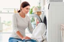 Woman putting clothes into washing machine