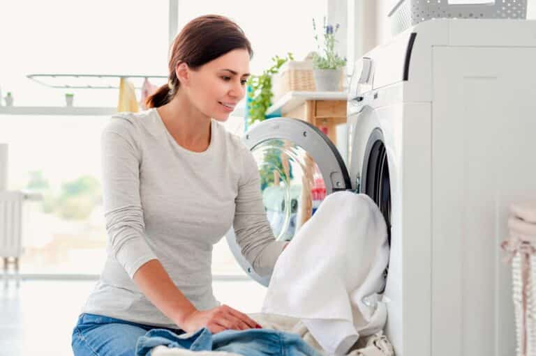 Woman putting clothes into washing machine