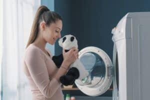 Woman washing a panda plush in the washing machine