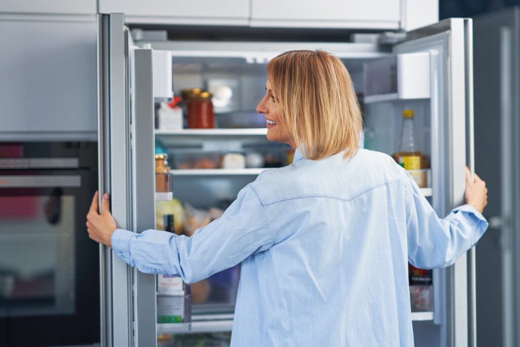 Young adult woman in the kitchen with the fridge