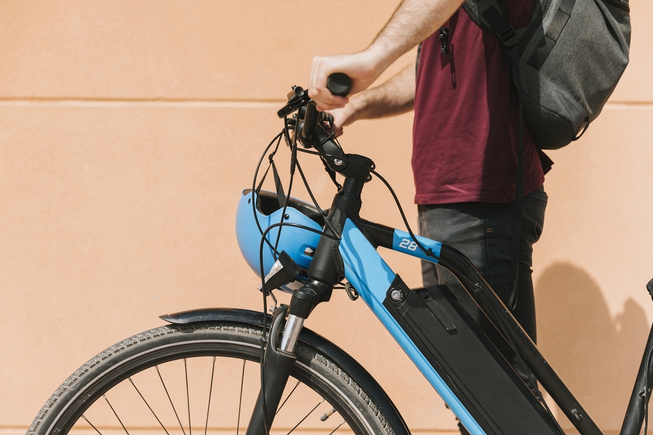 Un cycliste debout à coté de son vélo électrique