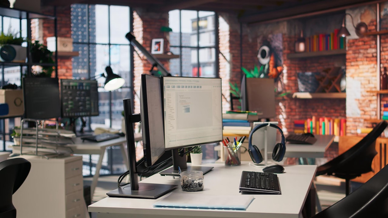 Un environnement de travail avec plusieurs bureaux où sont disposés ordinateurs, claviers, casques, etc..