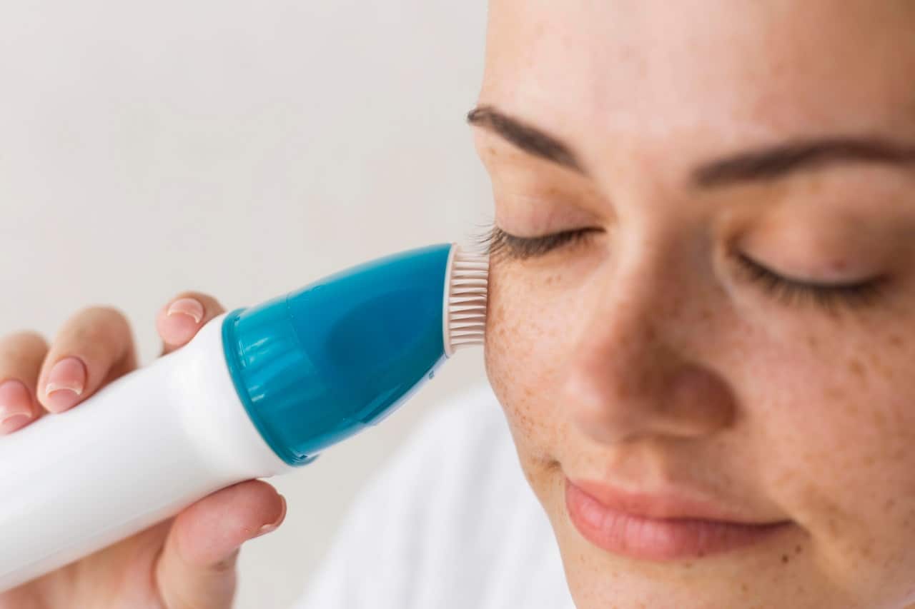 Gros plan sur le visage d'une jeune femme qui utilise un appareil anti-acné