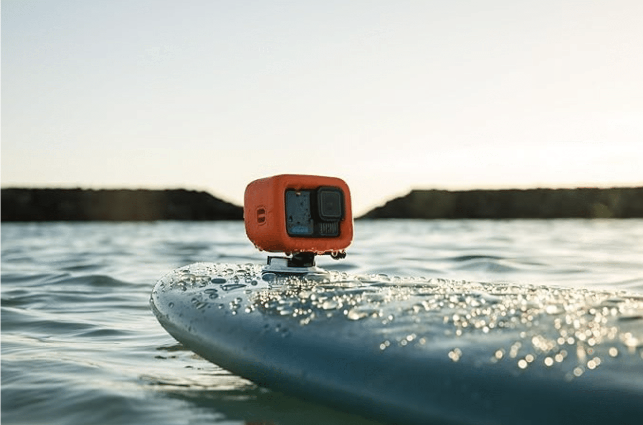 Une caméra de la marque GoPro accrochée à une planche de paddle sur un lac.