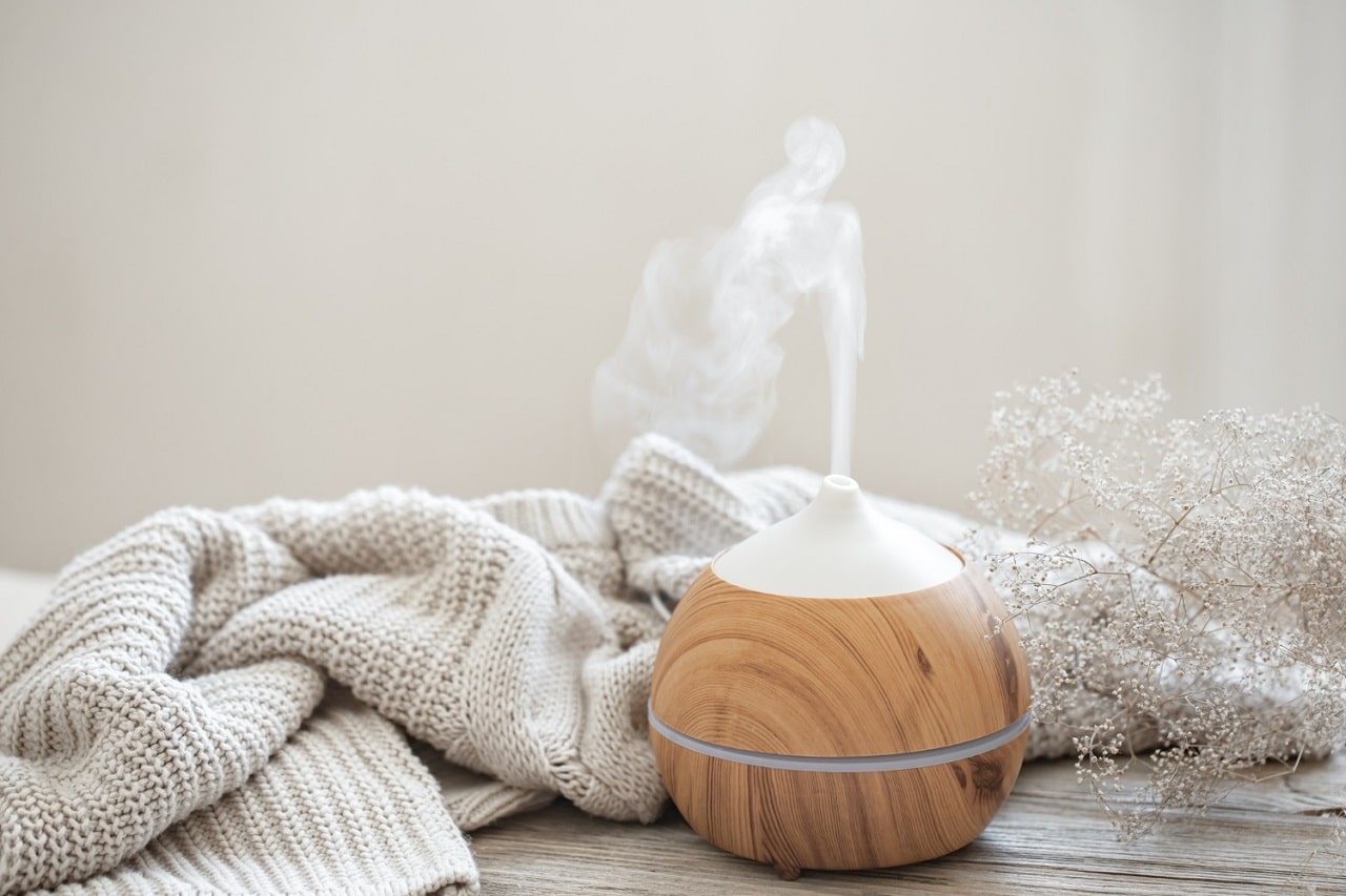 Un diffuseur d'huiles essentielles devant une serviette éponge beige