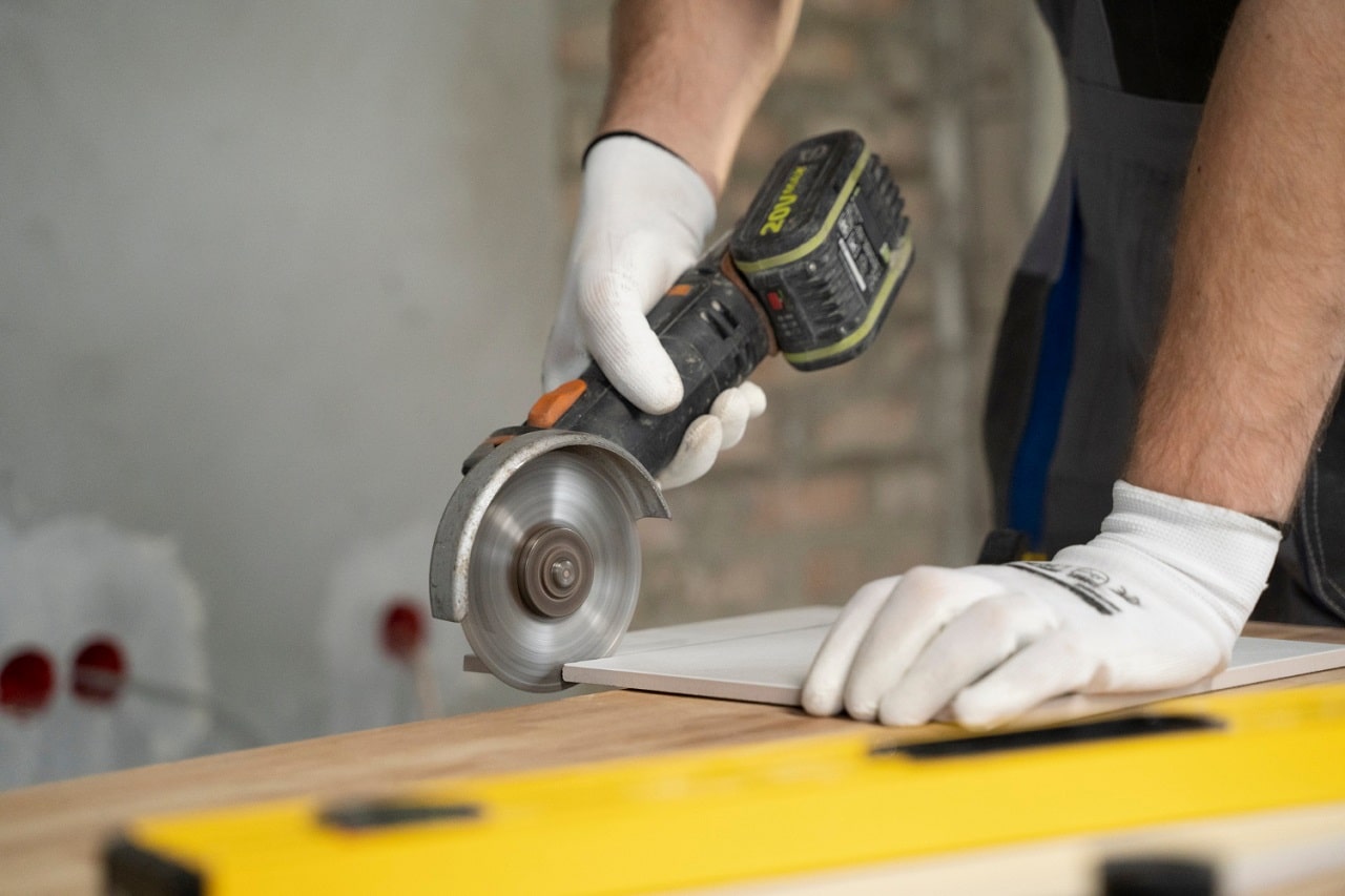 Un bricoleur utilisant une meuleuse sans fil pour couper du carrelage