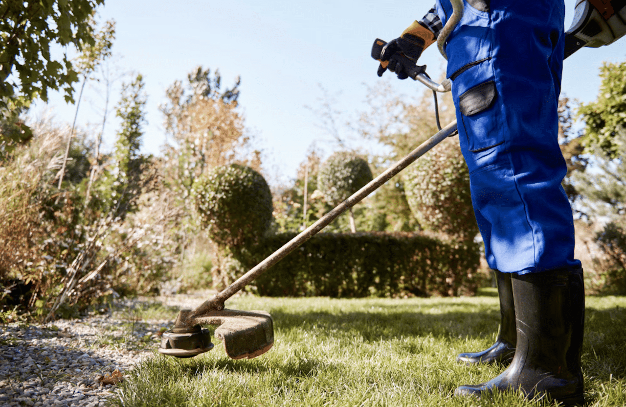 Un homme qui utilise une débroussailleuse dans son jardin.